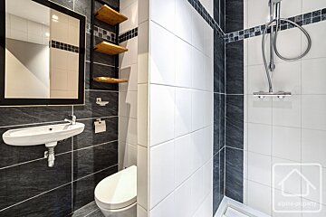 A bathroom with black and white tiles and a sign that says alpha-property