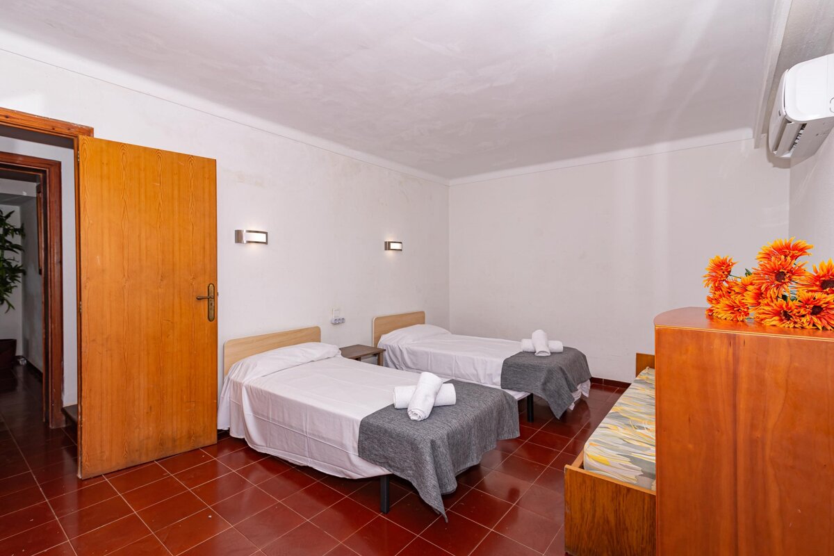 A bedroom with two beds and a dresser with flowers on it