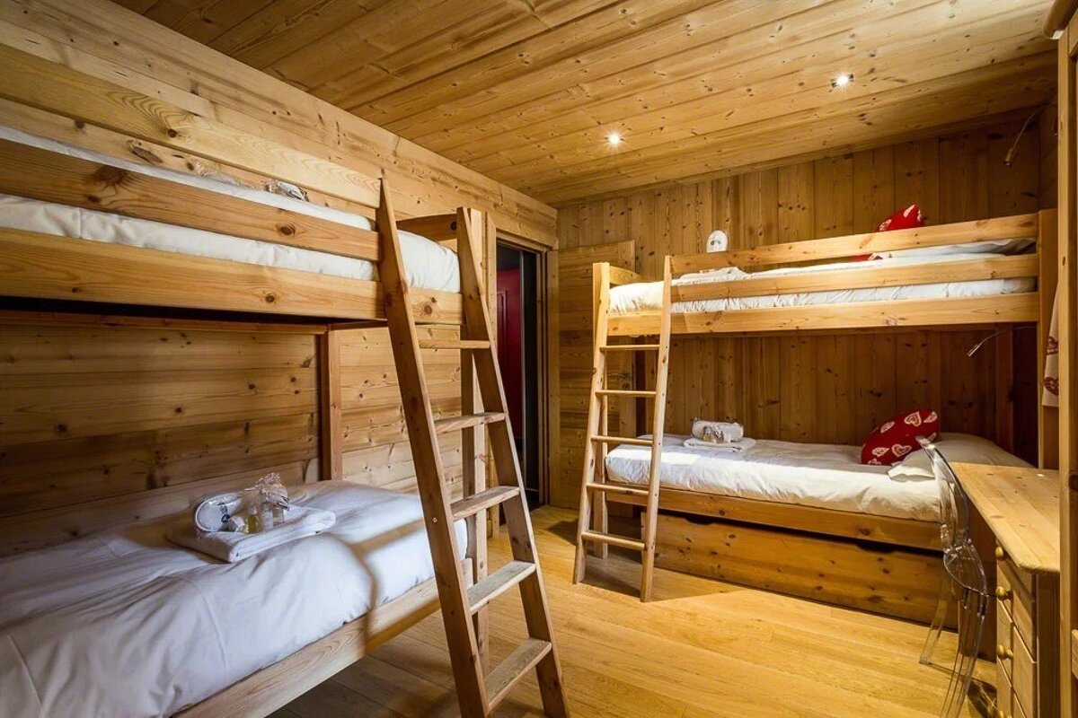 Rustic wooden bedroom featuring two sets of sturdy pine bunk beds with built-in ladders.