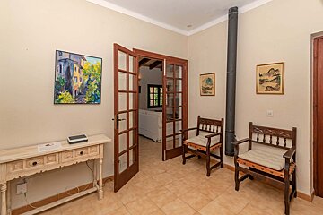 A hallway with a painting on the wall and two chairs