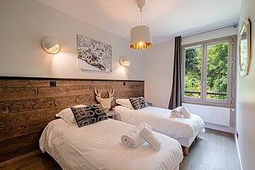 A bedroom with two beds and a picture of a snow leopard on the wall
