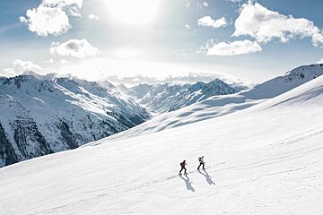 Two people skiing down a snow covered mountain