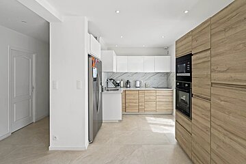 Bright, modern kitchen with light wood and white cabinetry, a marble backsplash, stainless steel appliances, and tiled floors.