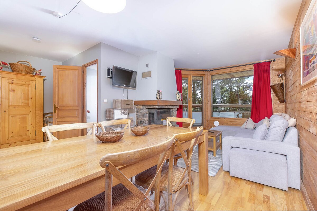 A living room with a table and chairs and a flat screen tv