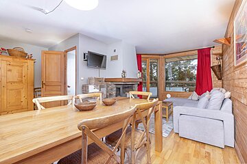 A living room with a table and chairs and a flat screen tv