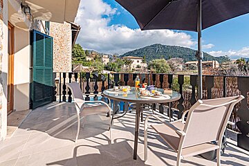 A balcony with a table and chairs and a mountain in the background