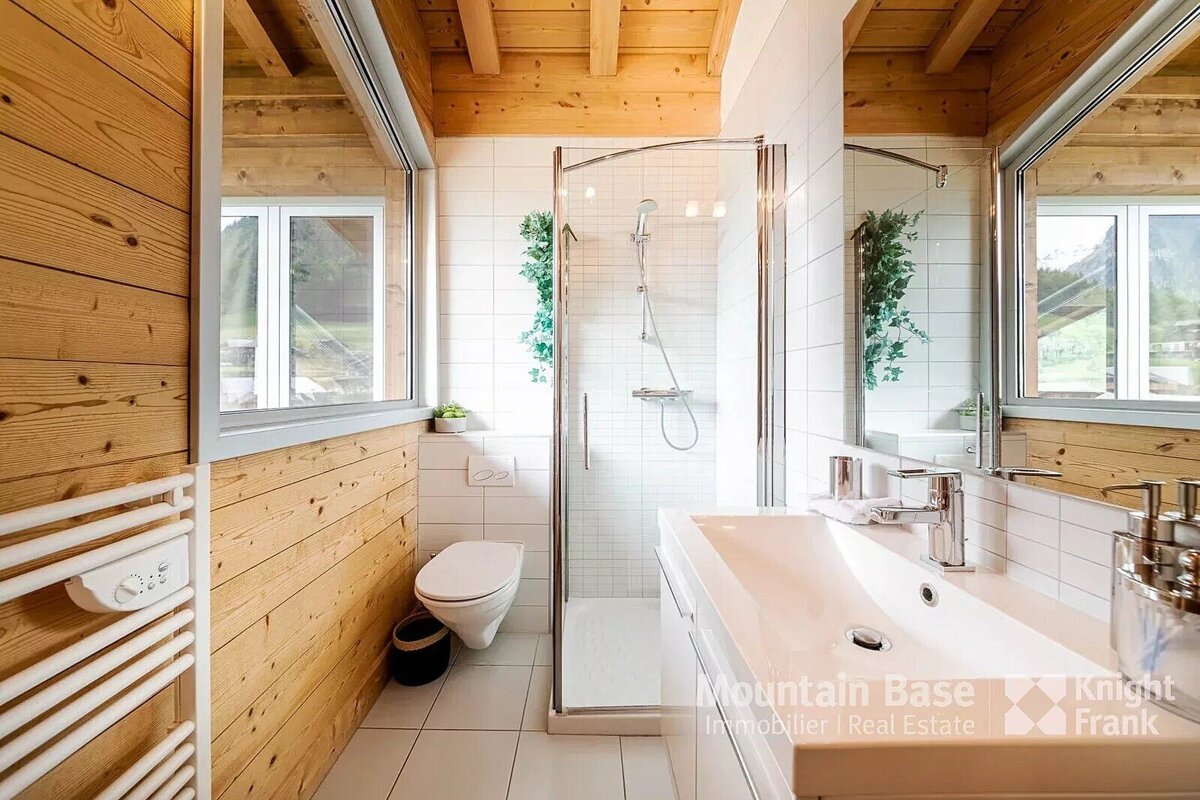 A bathroom with a toilet a sink and a shower says mountain base immobilier real estate