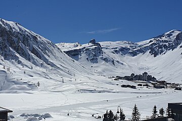 A snowy mountain with a ski resort in the background