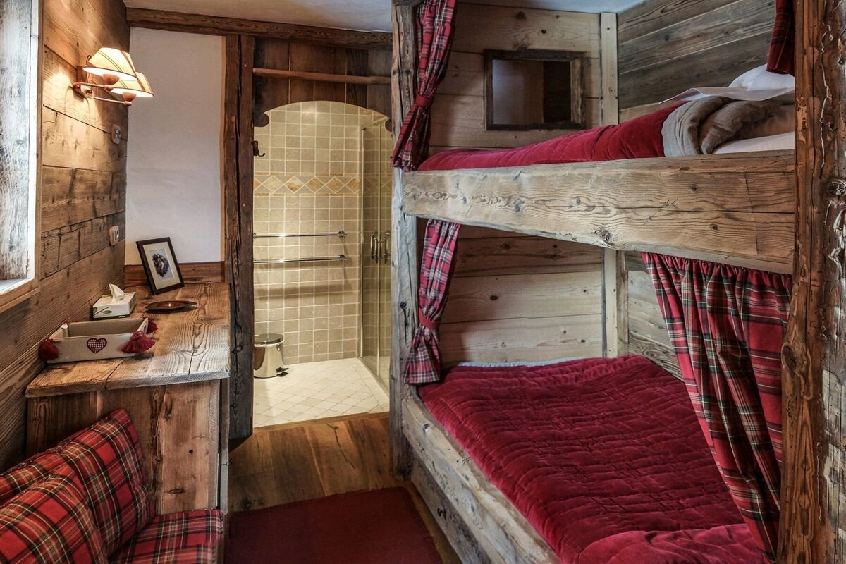 A bunk bed in a wooden cabin with red plaid curtains