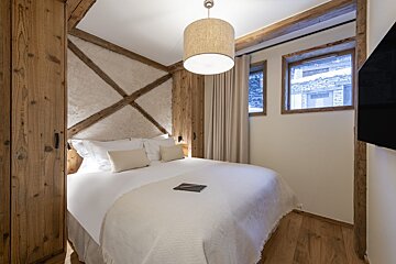 A bedroom with a large bed and a lamp hanging from the ceiling