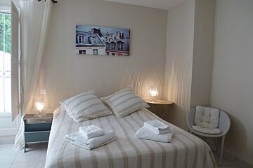 A bedroom with a painting on the wall above the bed