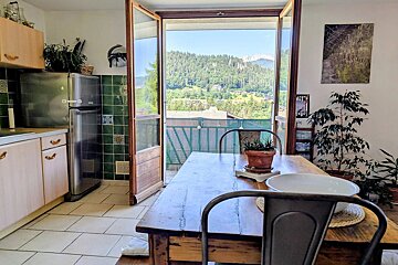 Rustic dining room with open French doors offering a scenic view of lush green mountains.