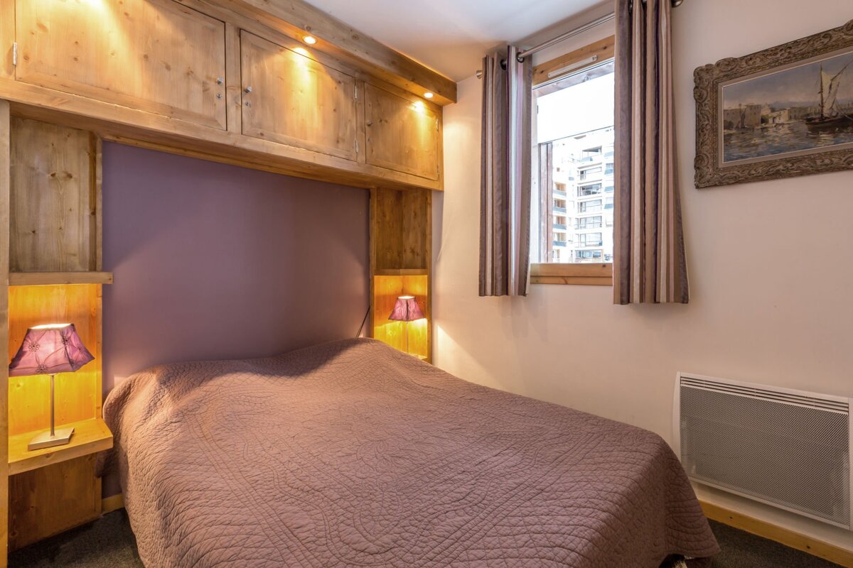 A small bedroom with a bed and two lamps