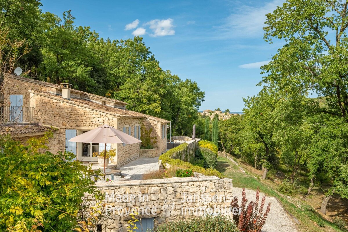 A stone house with an umbrella in front of it that says provence immobilier
