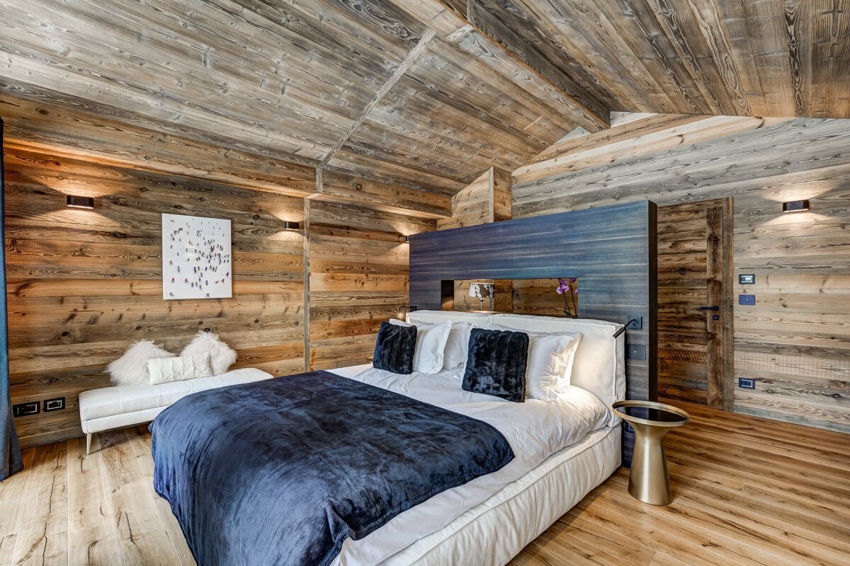 A bedroom with wooden walls and a bed with a blue blanket