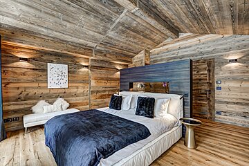 A bedroom with wooden walls and a bed with a blue blanket
