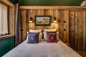 A bedroom with a painting on the wall above the bed