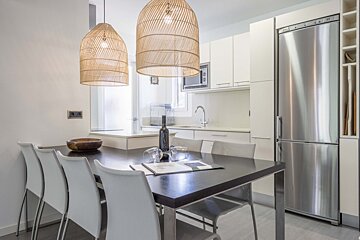 A kitchen with a table and chairs and a stainless steel refrigerator