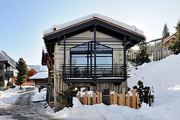 A snowy house with a fence in front of it