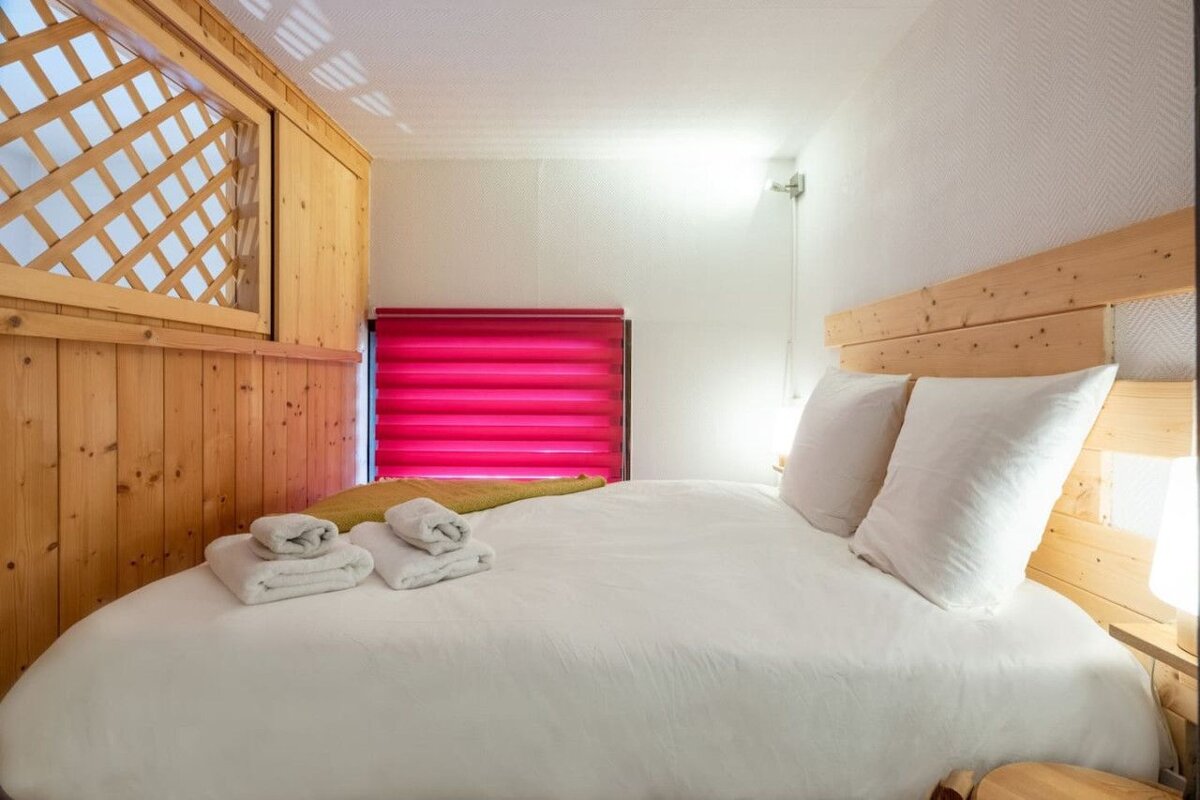 A bedroom with a bed and a window with pink blinds