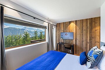 A bedroom with a large bed and a television on the wall