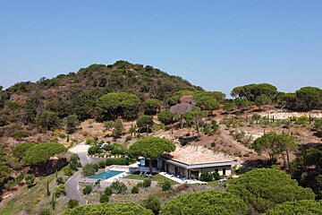 A house sits on top of a hill surrounded by trees