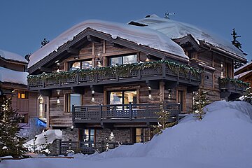 A large house with snow on the roof and balconies