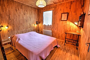 A bedroom with wood paneling and a bed with a pink blanket