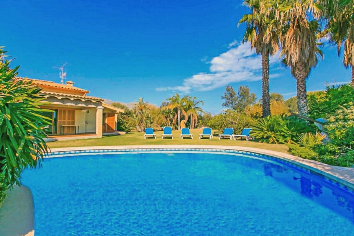 A large swimming pool surrounded by lawn chairs and palm trees