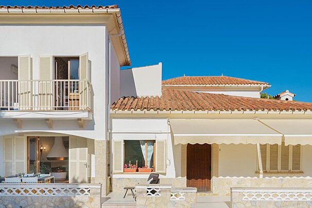 A white house with a red tile roof and a balcony