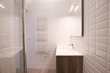 A bathroom with white tiles and a sink