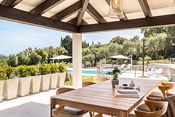 A table with a book on it sits on a patio overlooking a pool