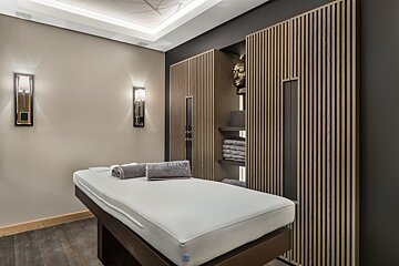 A massage table with a mattress and towels that say luxury