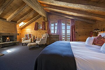A bedroom with a bed and chairs and a fireplace