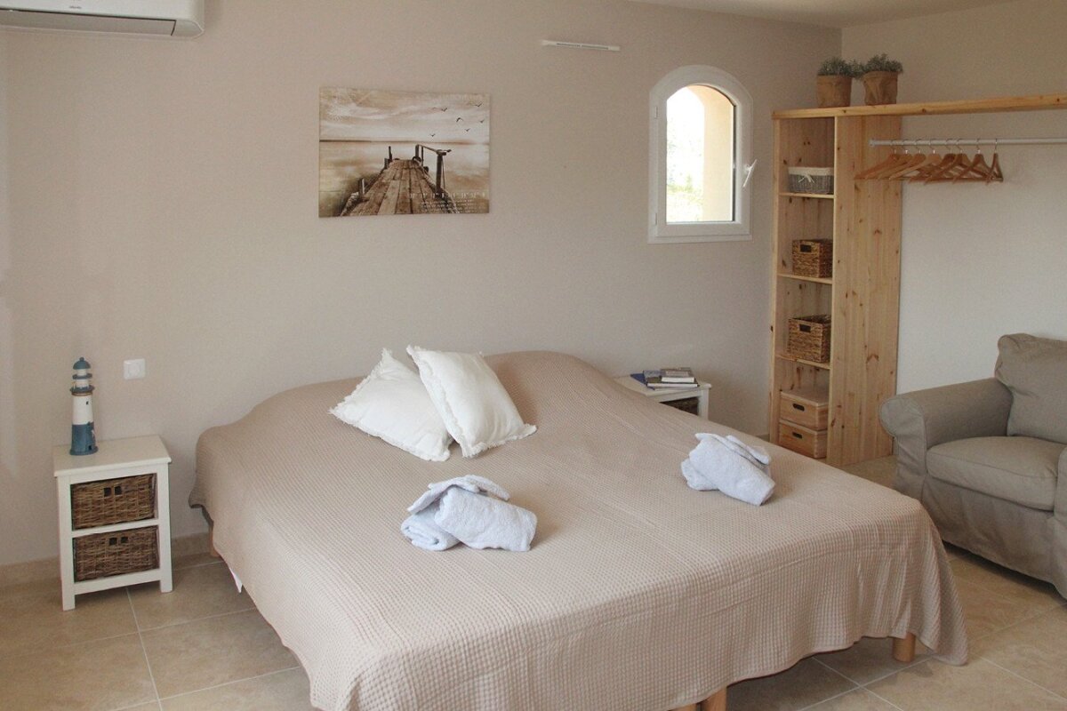 A bedroom with a painting of a pier on the wall above the bed