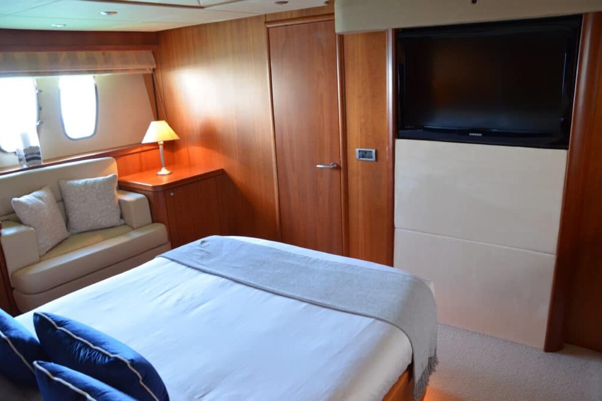 A bedroom with a bed a couch and a flat screen tv