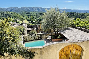 A swimming pool is surrounded by a stone wall with mountains in the background