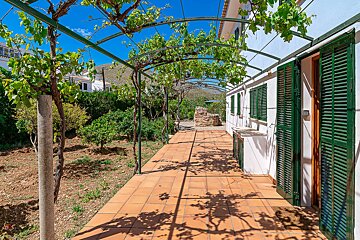 A white house with green shutters and a covered walkway