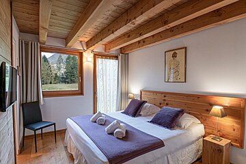 A bedroom with a painting of a woman on the wall above the bed