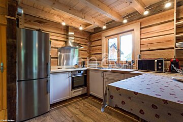 A kitchen in a log cabin with a stainless steel refrigerator