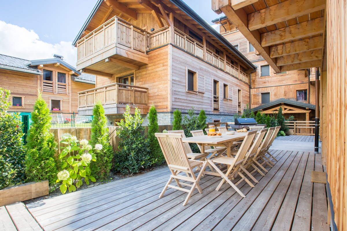 A wooden deck with a table and chairs in front of a wooden building