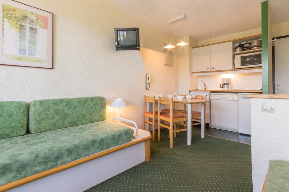 A kitchen with a table and chairs and a television