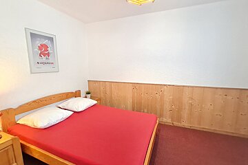 A bedroom with a red bed and a poster on the wall that says switzerland