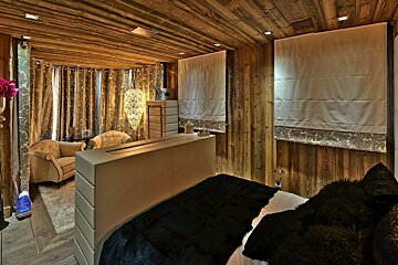 A bedroom with wooden walls and a black bed