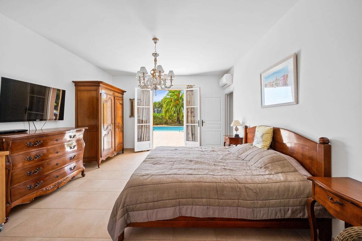 A bedroom with a large bed a dresser and a flat screen tv