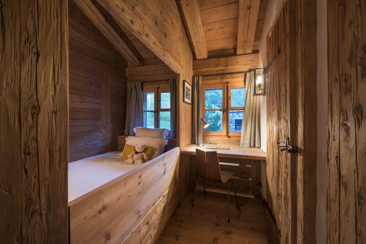 A wooden bedroom with a teddy bear on the bed