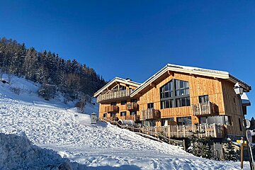 A snowy hillside with a wooden building in the foreground