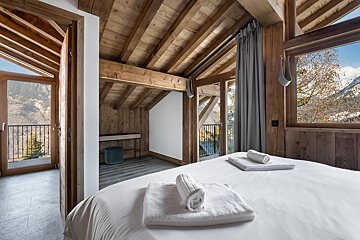 A bedroom with a large bed and a balcony