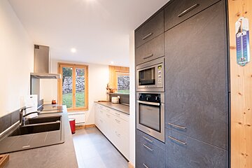 A kitchen with a thermometer hanging on the wall that says degrees