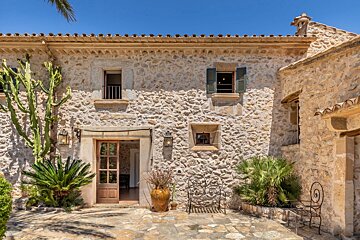 The front of a stone building with shutters on the windows